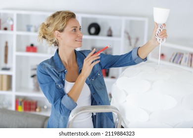 Woman Changing The Ceiling Lamp