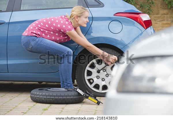 Woman Changing Flat tire On\
Car