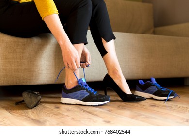 Woman changing high heels, office shoes after working day while sitting on the couch, ready to take a walk or run - Powered by Shutterstock