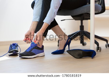 Woman changing high heels, office shoes after working day while sitting on the chair, ready to take a walk or run 商業照片 © 