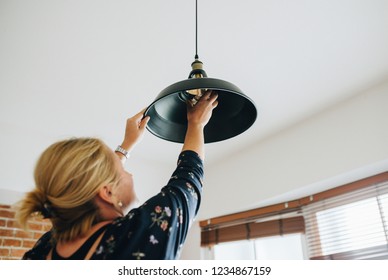 Woman changing a light bulb in her home