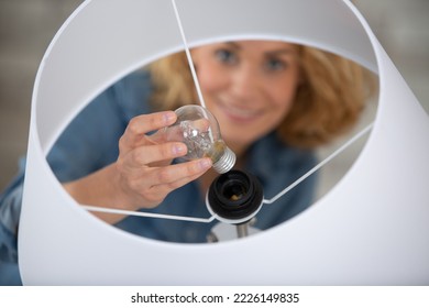 woman changing a light bulb in her home