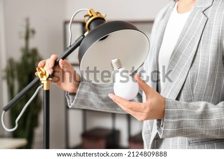 Woman changing light bulb in office lamp, closeup