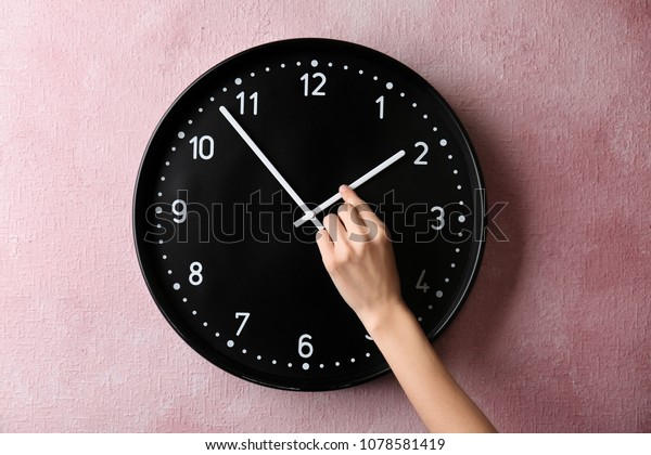 Woman changing time on\
big wall clock