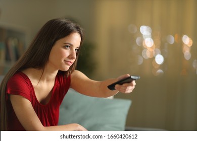 Woman Changing Tv Channels With Remote Control Sitting On A Couch At Home In The Night