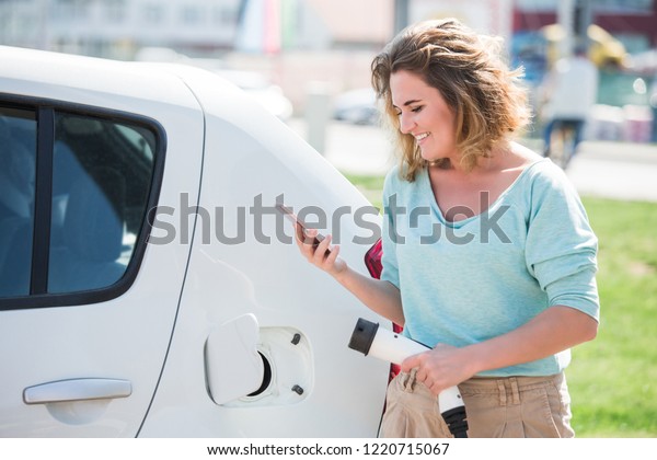 Woman\
charges an electric car at the charging\
station