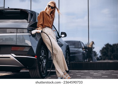 Woman charging electric car and holding charger - Powered by Shutterstock