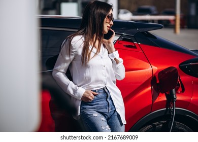 Woman Charging Electric Car And Talking On The Phone