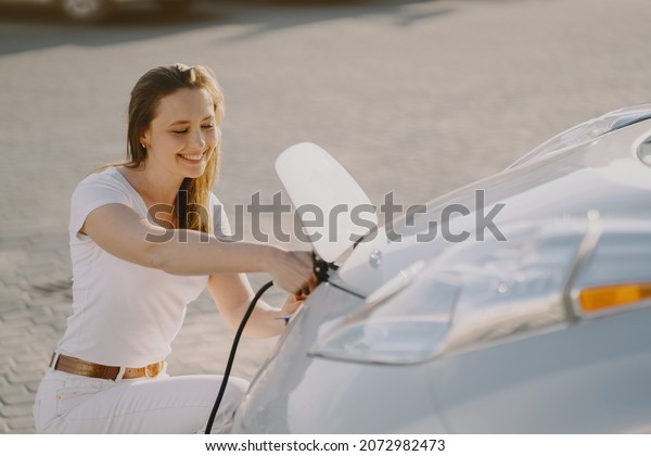 Woman\
charging electro car at the electric gas\
station