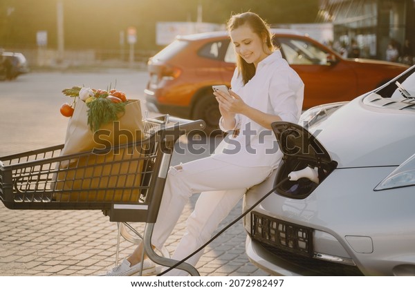 Woman\
charging electro car at the electric gas\
station