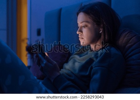 Woman chatting and surfing on internet with smartphone late at night, because of blackout