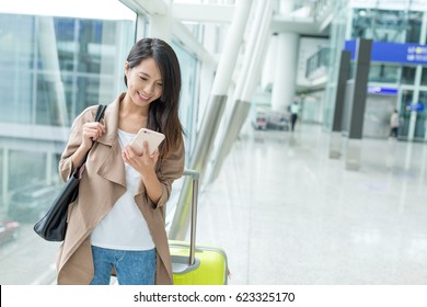 Woman Check Flight Number On Mobile Phone In Airport