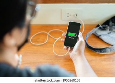 Woman Check Her Smart Phone Battery While Charging From The Usb Power Socket On The Wall