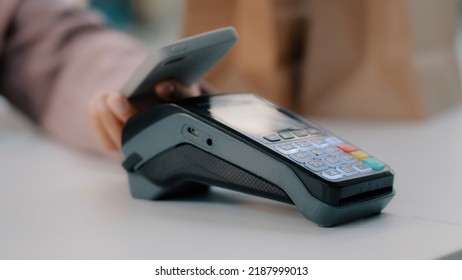 Woman At Check-in Desk At Counter Pays With Smartphone Through NFC Contactless Payment From Mobile Phone In Bar Cafe Purchase Of Food Products Pay By Card From Telephone Close-up Focus On Terminal