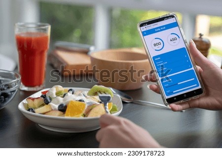 Woman checking calories and nutrients app on her phone while having a meal. Professional Nutritionist.