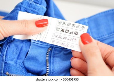 Woman Checking The Care Label Of A Pair Of Blue Jeans