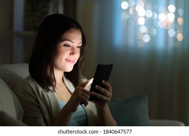 Woman Checking Cell Phone Sitting On A Sofa In The Night At Home