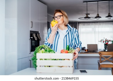 Woman checking fresh organic bell pepper from a wooden box with fresh vegetables. Local farmer healthy food. New Start of a healthy life, weight loss concept. Online home food delivery. Copy space - Powered by Shutterstock