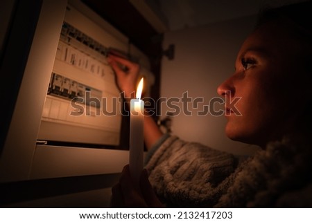 Woman checking fuse box at home during power outage or blackout. No electricity concept