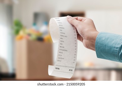Woman checking a grocery receipt and bag full of groceries in the background
