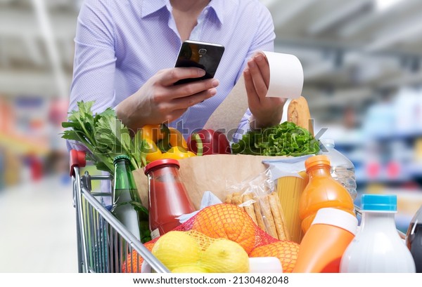 Woman\
checking the grocery receipt using her\
smartphone
