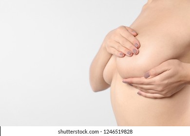 Woman checking her breast and space for text on white background, closeup