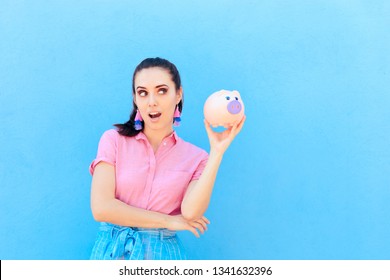 Woman Checking Her Financial Status Shaking Piggy Bank. Smart Millennial Thinking About Saving Money And Paying All Debt 
