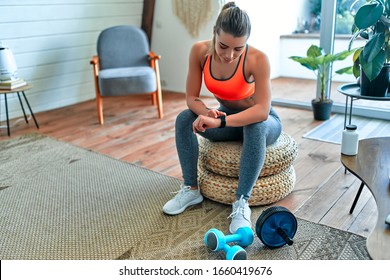 Woman Checking Her Workout Time At Home. Sport, Fitness, Lifestyle, Technology And People Concept - Woman Setting Heart-rate Watch.