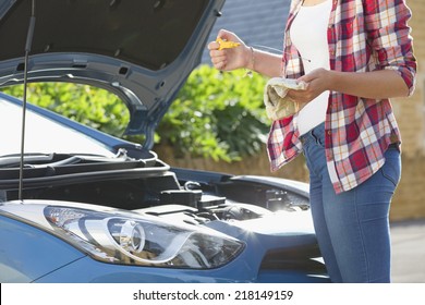 Woman Checking Oil Level In Car Engine