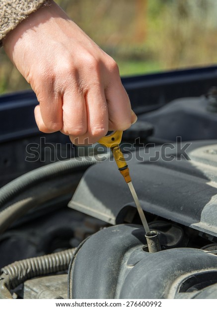 Woman checking oil level in\
car.