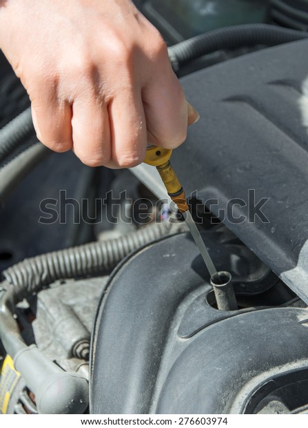 Woman checking oil level in\
car.
