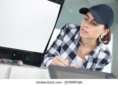 woman checking a printer machine at office