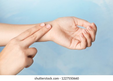 Woman Checking Pulse On Wrist Against Color Background, Closeup