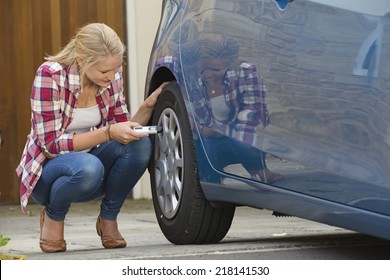 Woman Checking Tire Pressure On Car