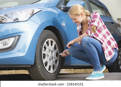 Woman Checking Tire Pressure On Car