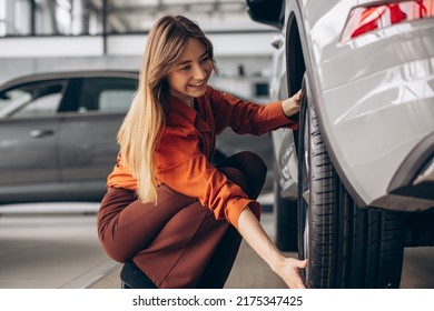 Woman Checking Tires In A Car Standing In A Car Showroom