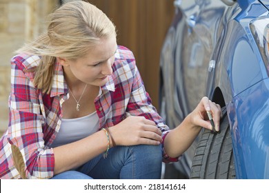 Woman Checking Tread Depth On Car Tire