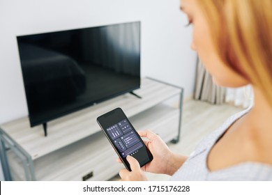 Woman Checking Tv Volume Settings Via Smart Tv Application On Smartphone