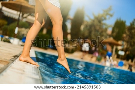 Woman checking water in the swimming pool.