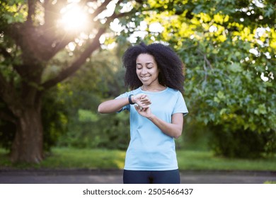 Woman checks her smartwatch in a sunny park, embracing fitness and relaxation through outdoor activity and positive energy.