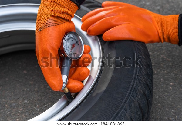 A woman checks the pressure\
in a car tire with a pressure gauge, close-up. Machine\
maintenance
