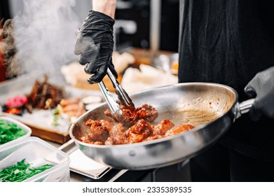 woman chef cooking chicken wings in a sauce in the kitchen - Powered by Shutterstock