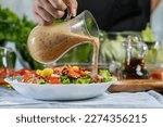 woman chef mix fresh baby cos salad and pour salad dressing in glass blow. Organic Vegetables mix all green salad In glass bowl. Breakfast fresh salad and clean vegetable.