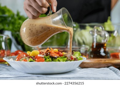 woman chef mix fresh baby cos salad and pour salad dressing in glass blow. Organic Vegetables mix all green salad In glass bowl. Breakfast fresh salad and clean vegetable.