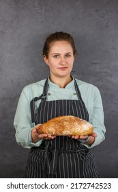 Woman Chef On A Dark Background. Mint Coat And Black Apron. Bread