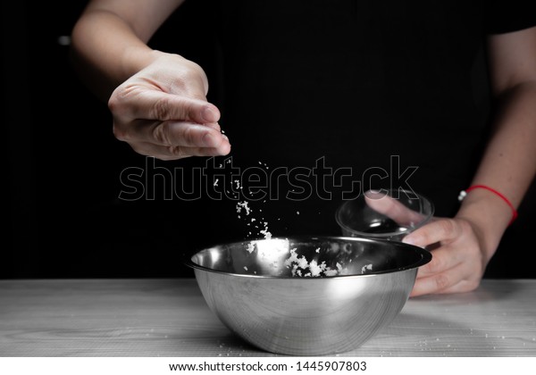 Woman chef sprinkles salt and seasoning for marinated fillet by condiment on a wooden table in the kitchen . Hand sprinkles salt for Preparing healthy food Cooking menu at Home .