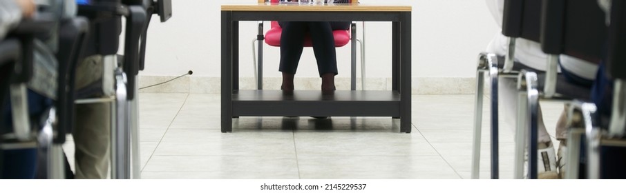 A Woman - A Chef Or A Teacher, Sitting At A Table, Gives A Lecture To Students Or Subordinates. Web Banner. Selective Focus. No Face. Indoors