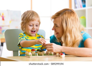 Woman And Child Boy Talking And Smiling While Playing With Educational Toys Together In Daycare Centre