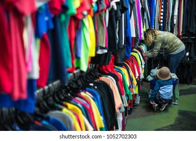 Woman And Child Browsing Through Clothing In A Thrift Store