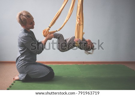 woman with child engaged in air yoga, yellow hammock, concept childhood and lifestyles